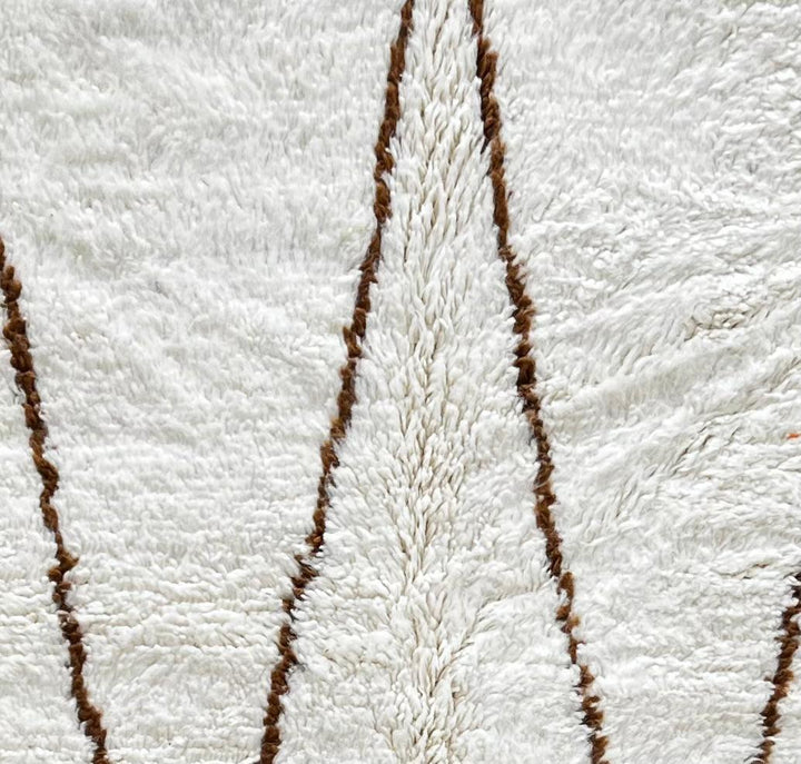 Round Moroccan Berber rug with white wool base and brown hanging geometric motifs, handmade wool carpet