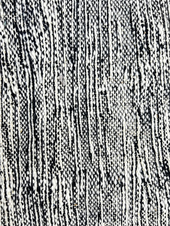 Handmade round Moroccan kilim rug with flatweave construction, featuring a black, and white zigzag geometric pattern.