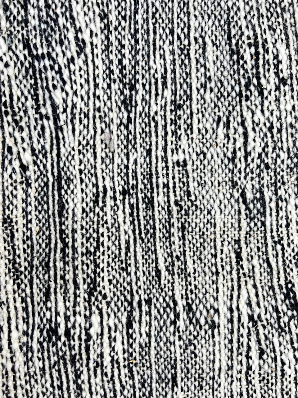 Handmade round Moroccan kilim rug with flatweave construction, featuring a black, and white zigzag geometric pattern.
