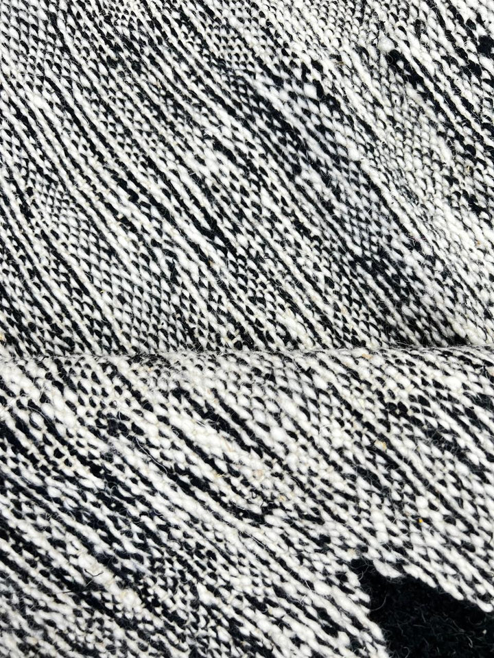 Handmade round Moroccan kilim rug with flatweave construction, featuring a black, and white zigzag geometric pattern.