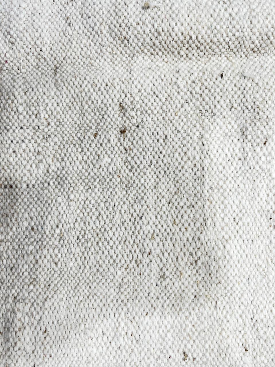 Handmade round Moroccan kilim rug with flatweave design, featuring an white wool base with abstract purple zigzag and black geometric motif.