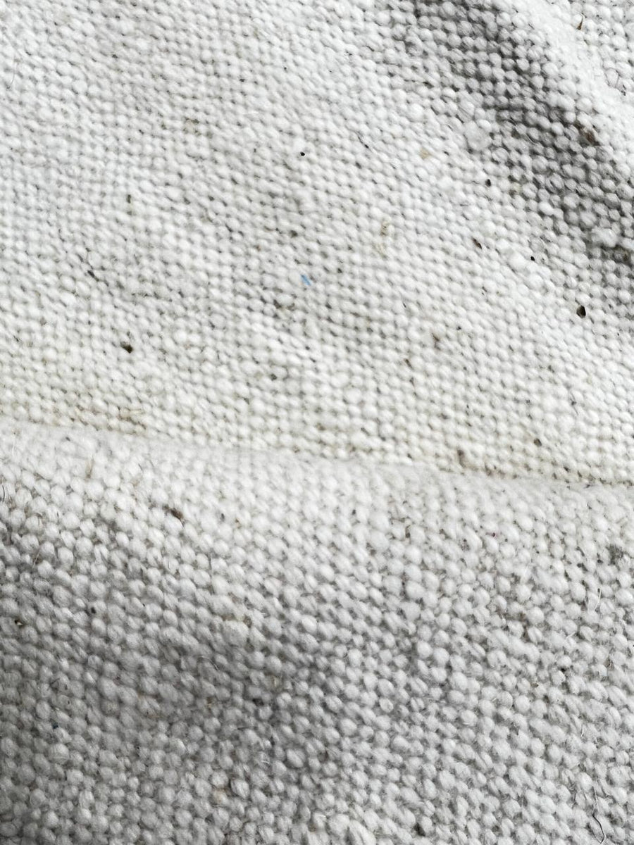 Handmade round Moroccan kilim rug with flatweave design, featuring an white wool base with abstract purple zigzag and black geometric motif.