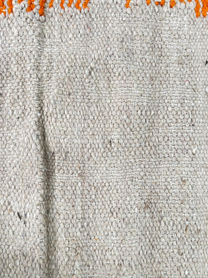 Handmade round Moroccan kilim rug with flatweave construction, featuring abstract earth tones in burnt orange, beige, and muted lavender.