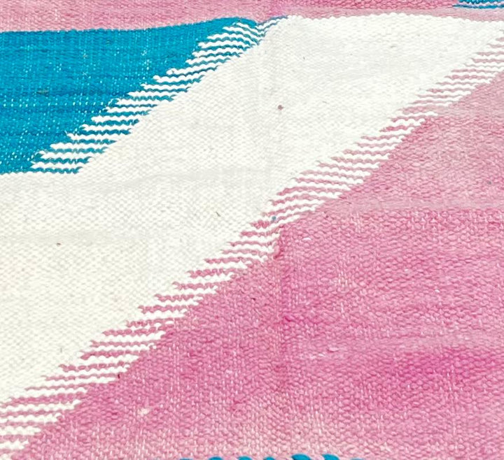 Handmade round Moroccan kilim rug with flatweave design, featuring modern pink and blue color blocks with white accents.