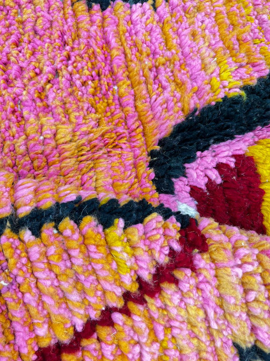 Round Moroccan rug with colorful abstract Berber design in red, pink, green, mustard, black, and cream, handmade wool carpet