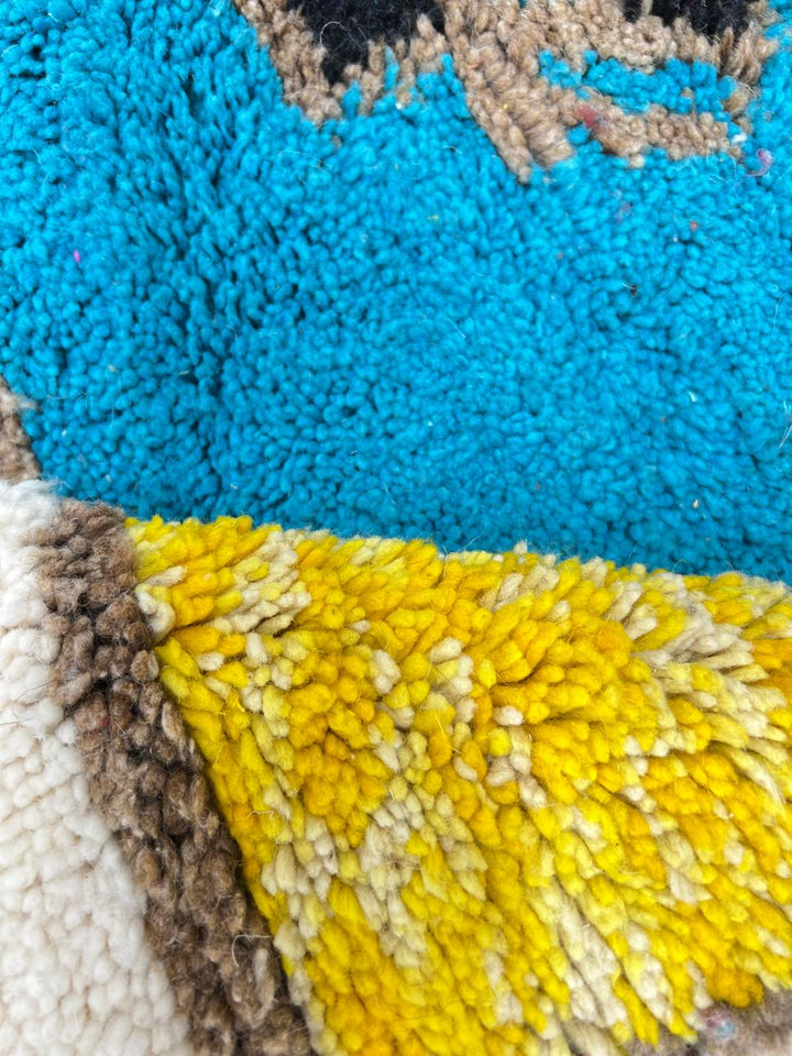Round colorful Moroccan wool rug with abstract geometric shapes in red, yellow, blue, green, purple, and white