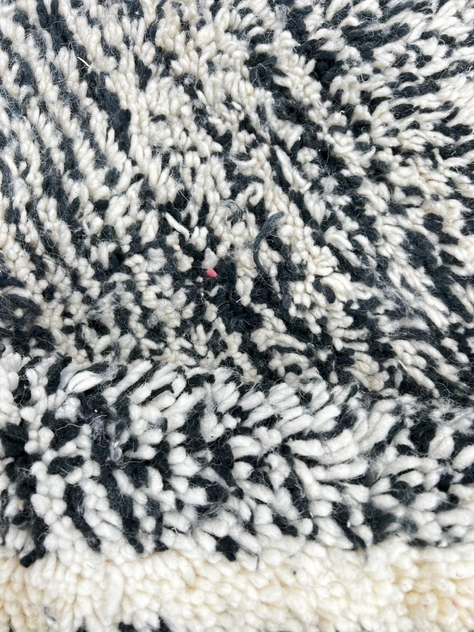 Round black and white Moroccan wool rug with geometric Berber diamond pattern on white background