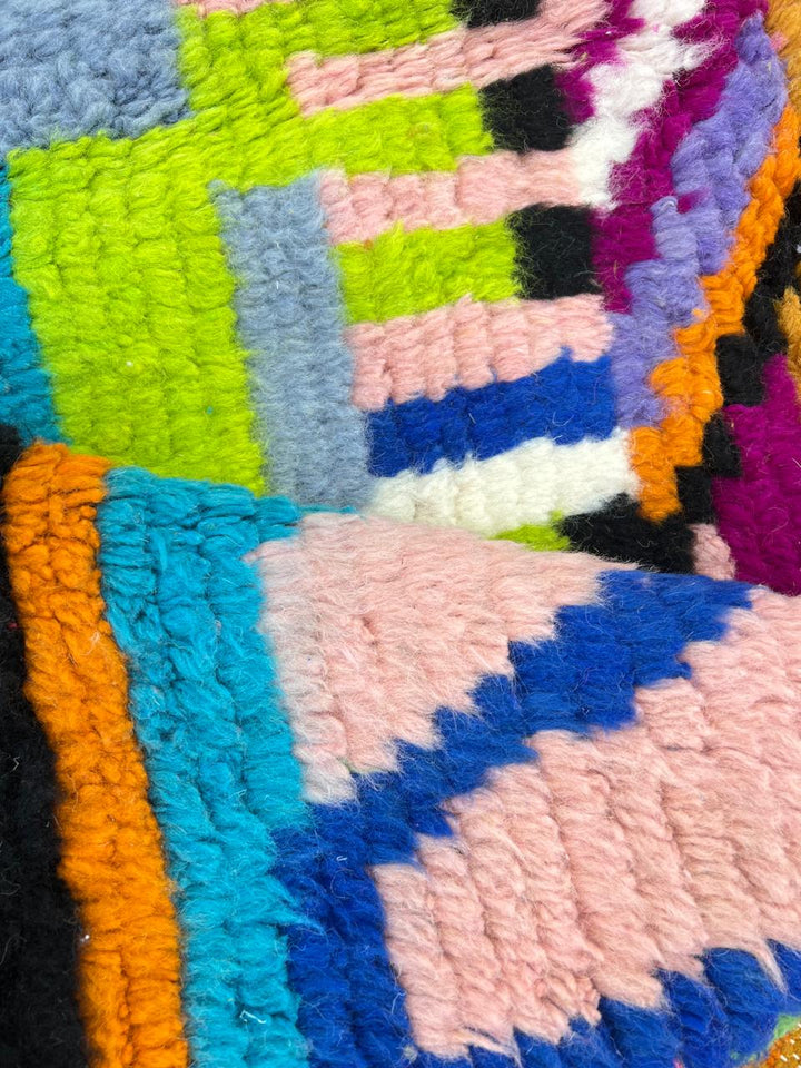 Round Moroccan wool rug with colorful abstract Berber design on pink background