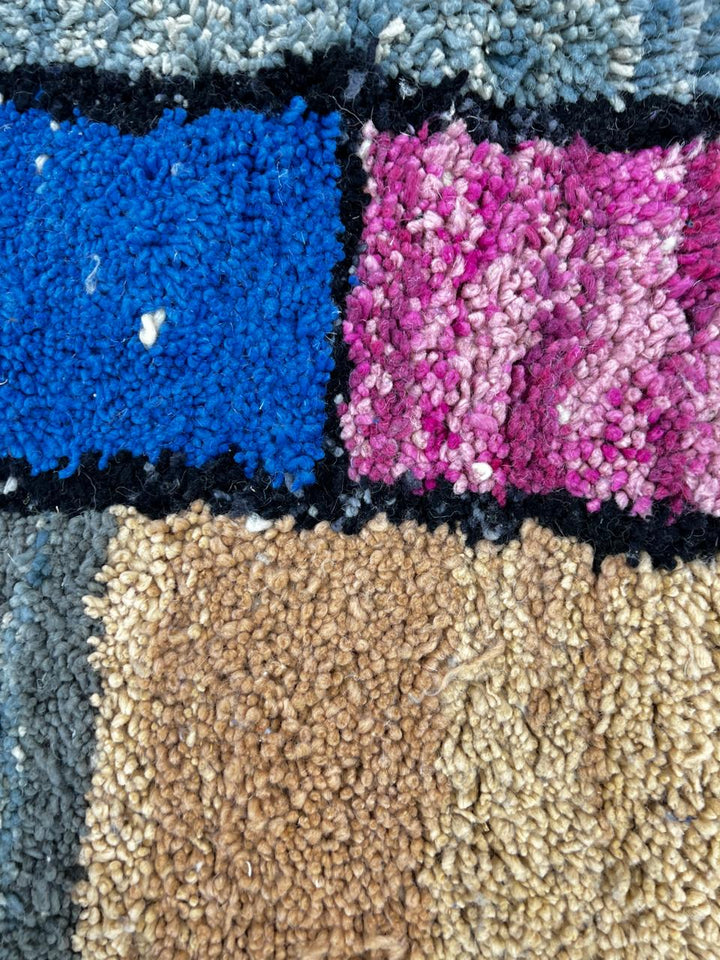 Handmade round Moroccan wool rug with colorful geometric block design, featuring vibrant orange, pink, blue, green, yellow, and black tones.