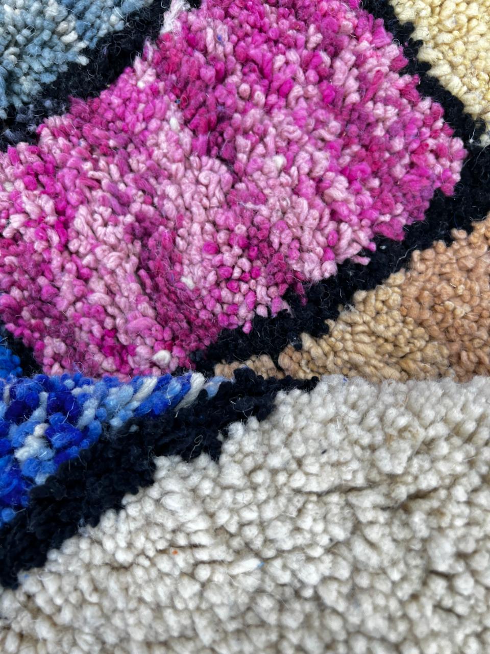 Handmade round Moroccan wool rug with colorful geometric block design, featuring vibrant orange, pink, blue, green, yellow, and black tones.