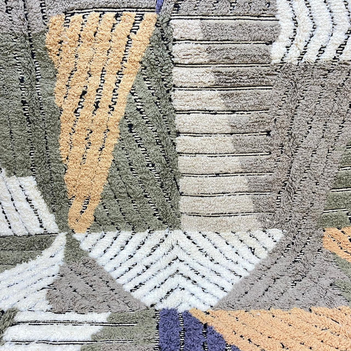 Round handmade Moroccan wool rug with geometric Berber pattern in green, beige, mustard, and blue tones on a white background 