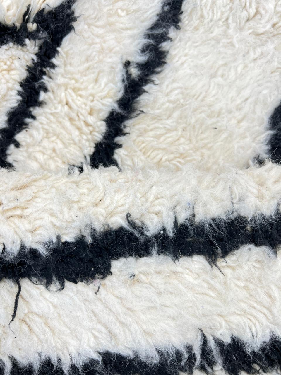 Round Moroccan wool rug in white with black Berber diamond pattern, handmade by artisans