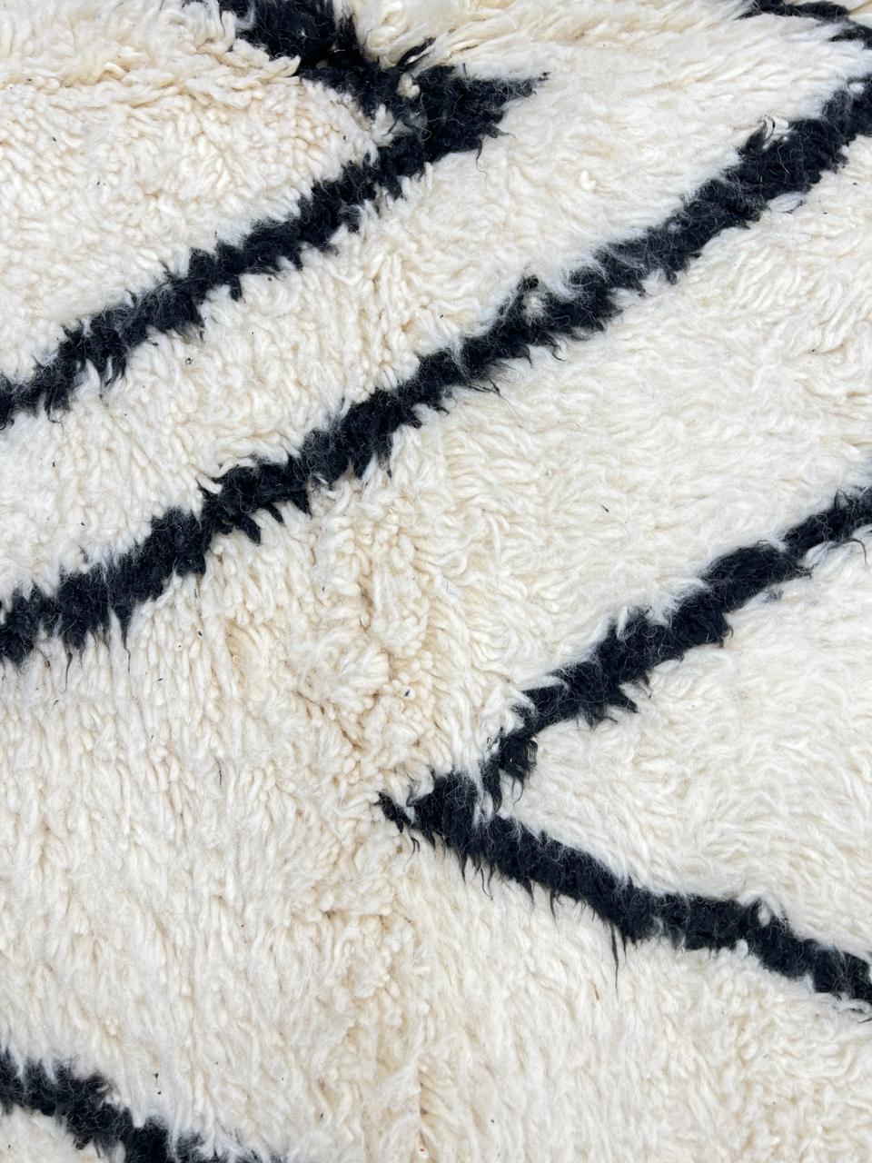 Round Moroccan wool rug in white with black Berber diamond pattern, handmade by artisans