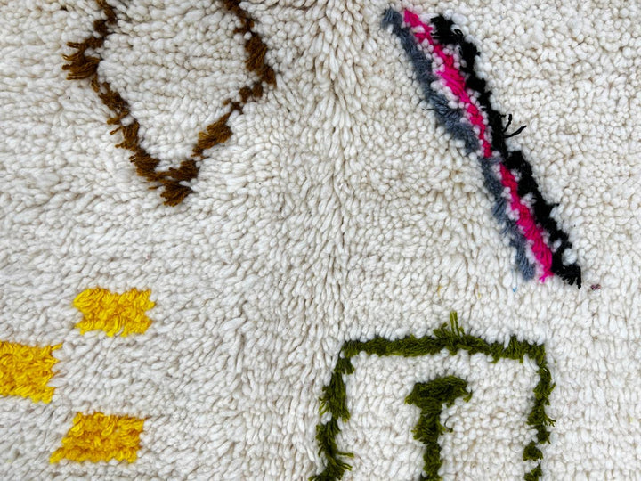 Round Moroccan wool rug with colorful Berber tribal symbols on a white background