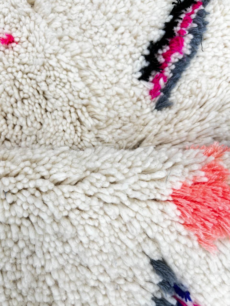 Round Moroccan wool rug with colorful Berber tribal symbols on a white background