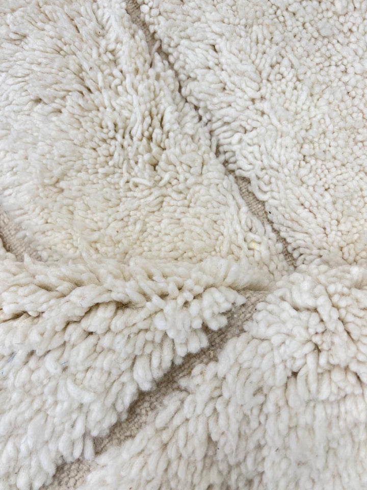 Round white Moroccan wool rug with subtle carved geometric line pattern