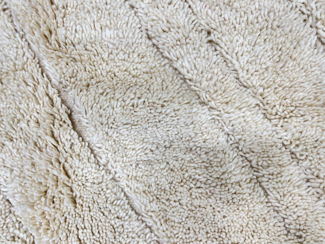 Round white Moroccan wool rug with subtle carved geometric line pattern