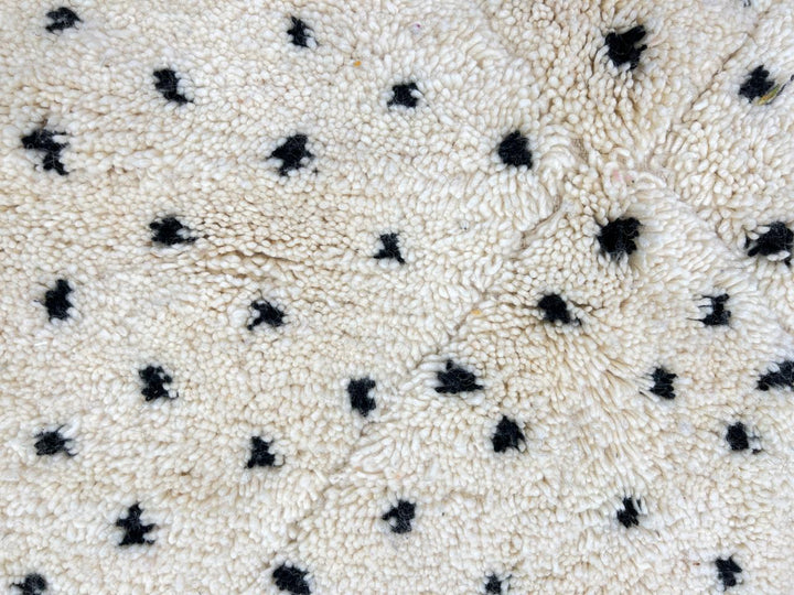 Round white Moroccan wool rug with black dotted motifs and carved diamond pattern
