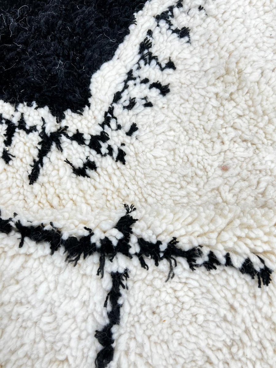 Round white Moroccan wool rug with black Berber symbols and geometric patterns on white background