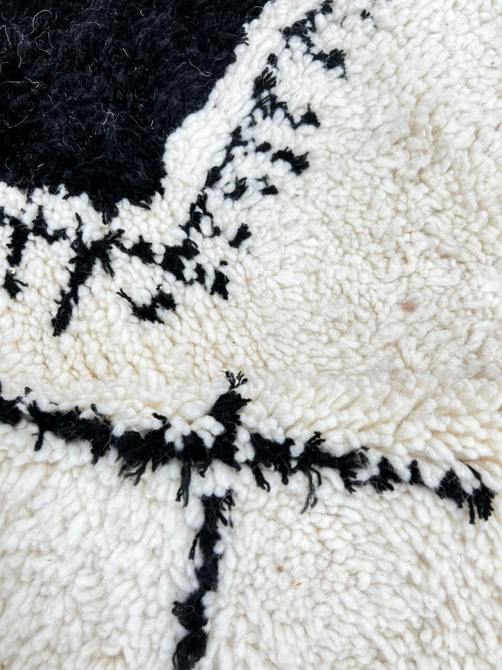 Round white Moroccan wool rug with black Berber symbols and geometric patterns on white background
