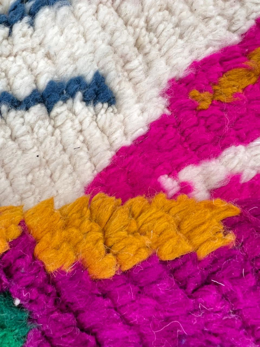 Round white Moroccan wool rug with colorful Berber symbols on white background