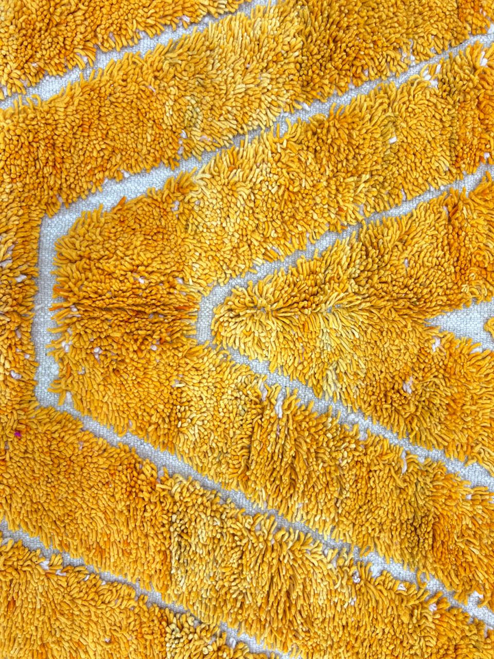 Round handmade Moroccan wool rug in golden yellow with chevron pattern