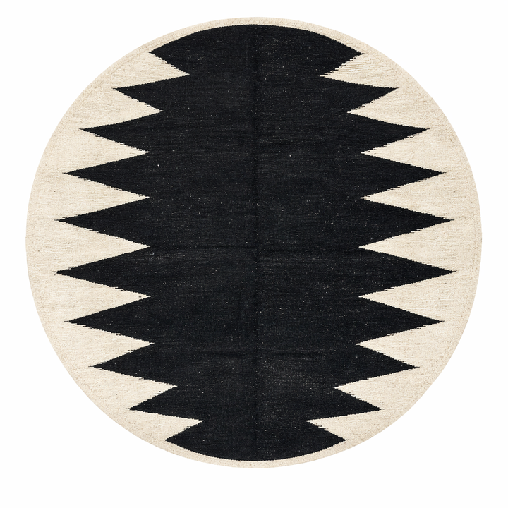Handmade round Moroccan flatweave kilim rug with black and white zigzag geometric pattern, woven from natural wool.