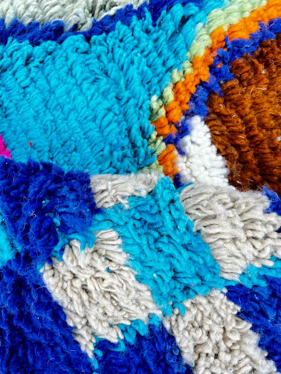 Round blue Moroccan wool rug with colorful Berber geometric patterns
