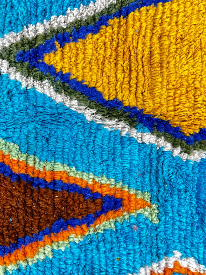 Round blue Moroccan wool rug with colorful Berber geometric patterns