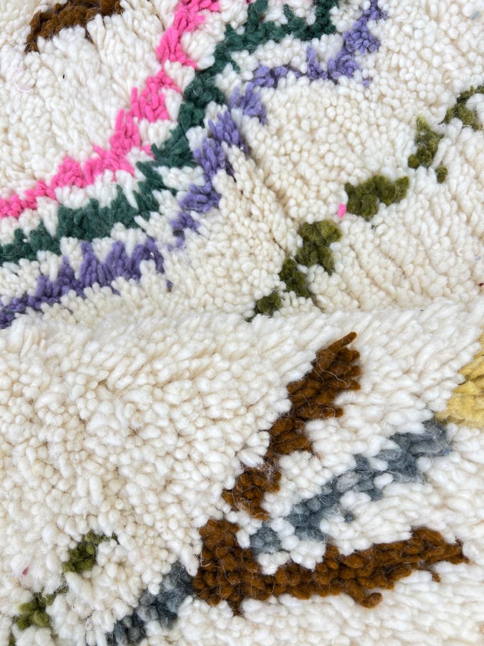 Round Moroccan Berber rug with white wool base and colorful tribal diamond motifs, handmade wool carpet