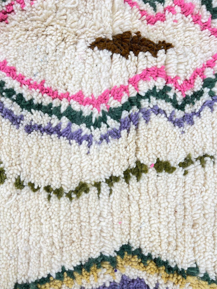 Round Moroccan Berber rug with white wool base and colorful tribal diamond motifs, handmade wool carpet