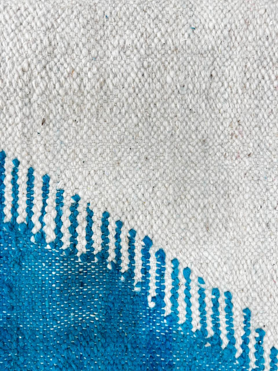 Handmade round Moroccan flatweave kilim rug with an white base and soft abstract shapes in muted purple and turquoise blue, woven from natural wool.