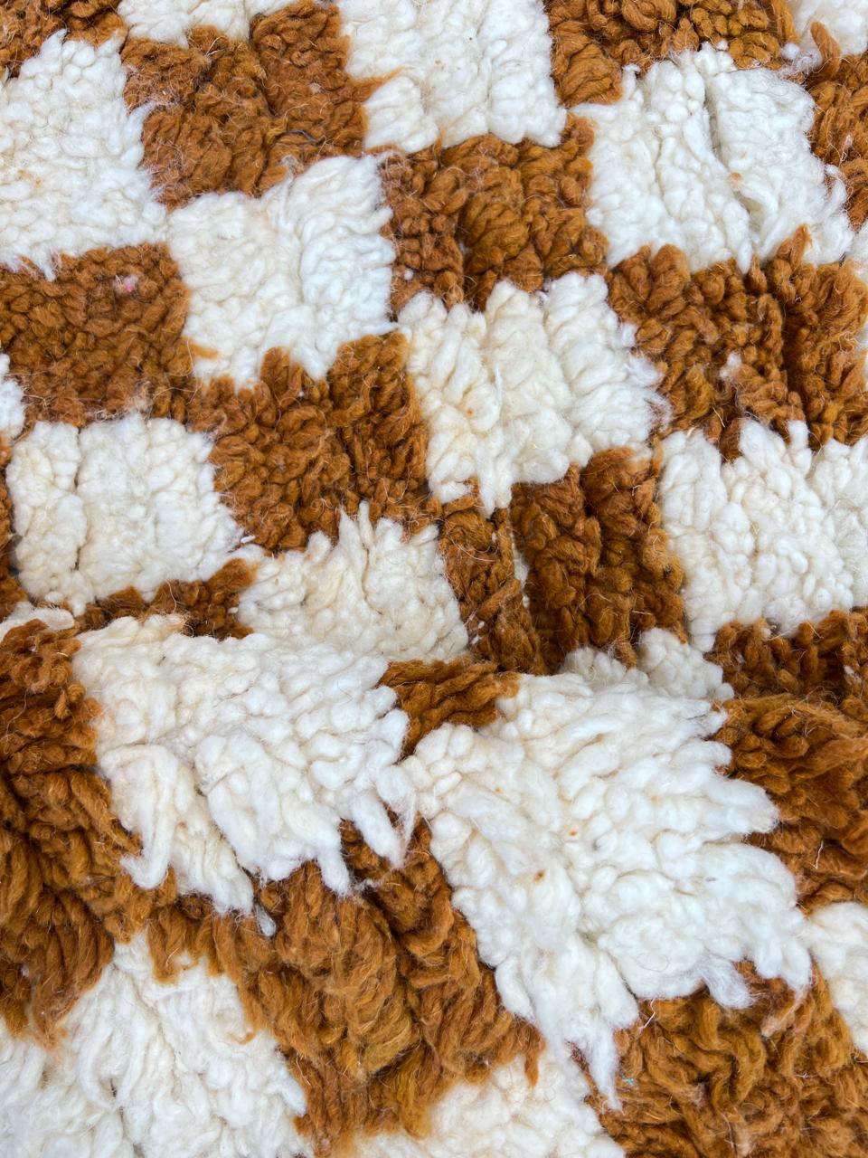 Round Moroccan wool rug with brown and white checkerboard pattern on a white background