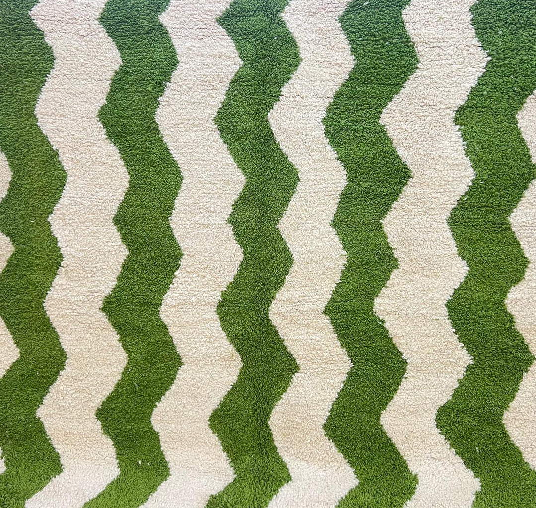 Round handmade Moroccan wool rug with green zigzag chevron pattern on cream background