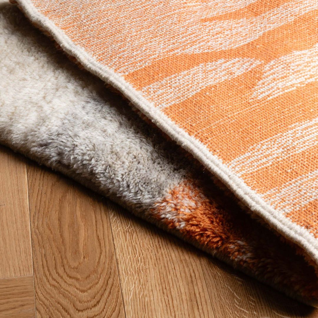 Handmade Moroccan wool rug with warm orange and terracotta hues, showcasing traditional Beni Mrirt design on a wooden floor.