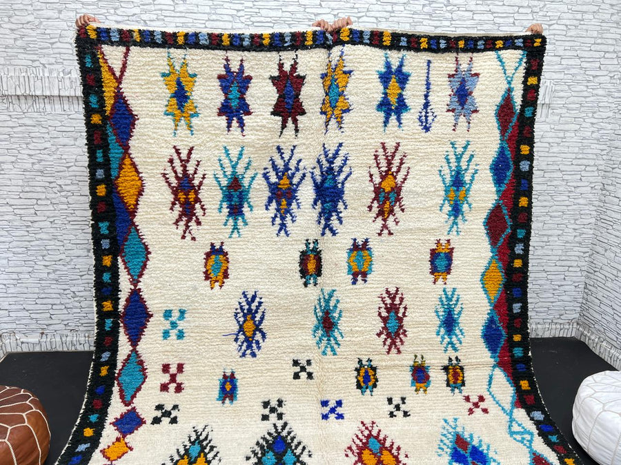 Handwoven Moroccan wool rug with colorful Berber tribal patterns and dark border