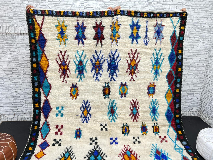 Handwoven Moroccan wool rug with colorful Berber tribal patterns and dark border