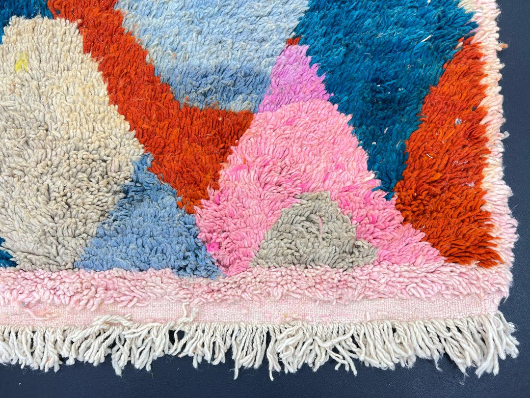 Handmade colorful Moroccan wool runner rug with abstract geometric pattern in red, blue, pink, and green tones