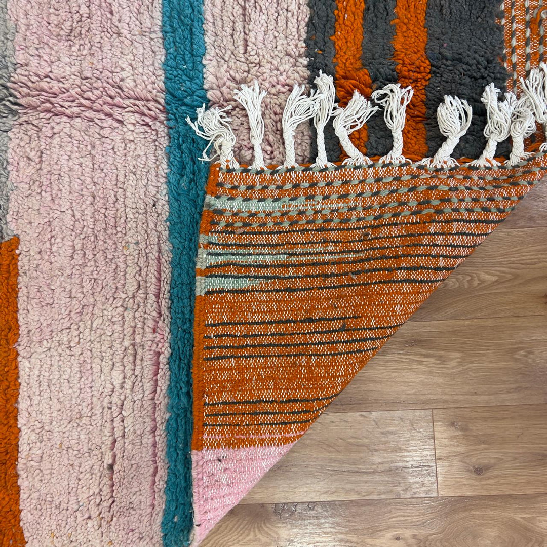 Vintage Moroccan wool rug 7.09 × 4.92 ft with striped design in blush pink, teal, charcoal, and burnt orange tones handmade Berber rug