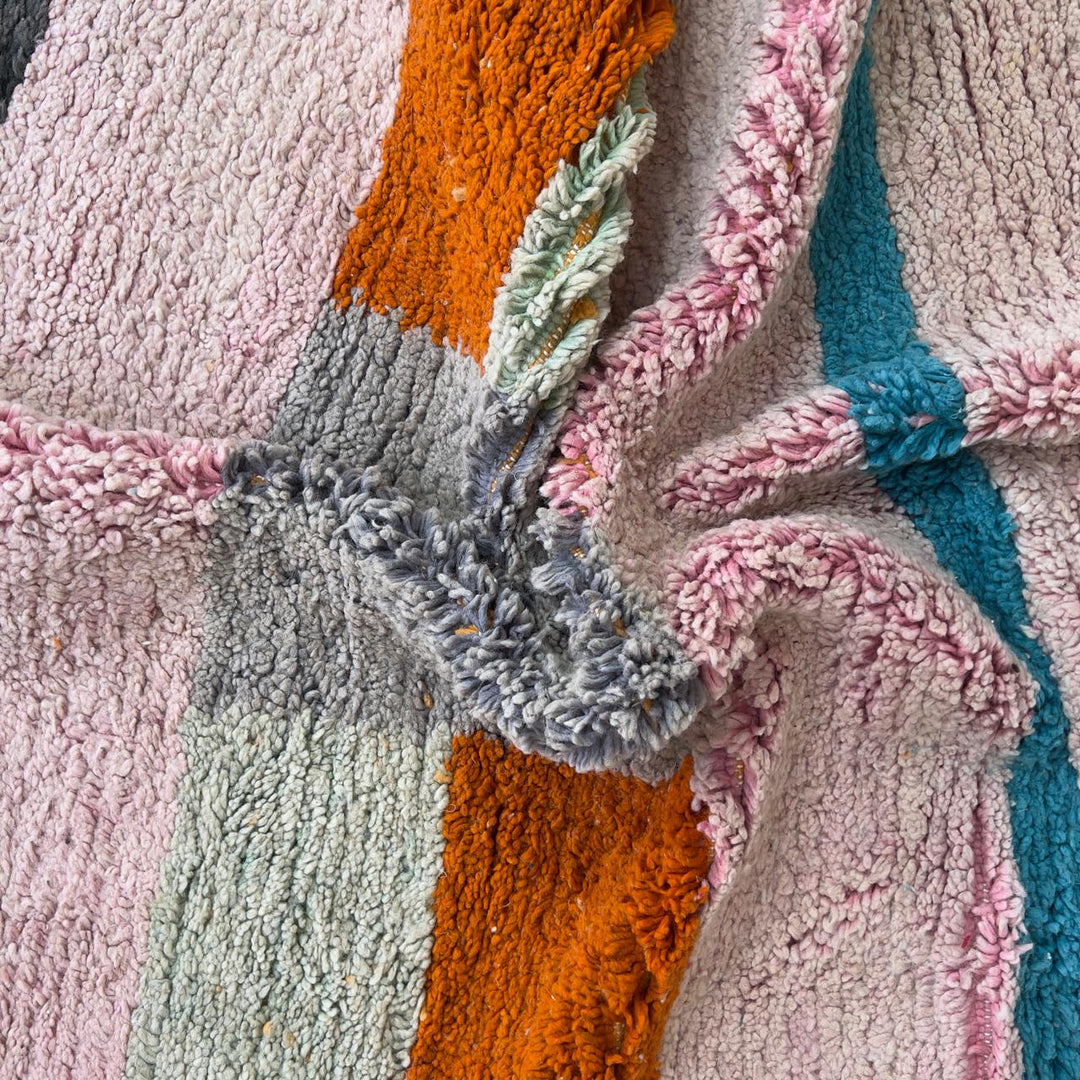 Vintage Moroccan wool rug 7.09 × 4.92 ft with striped design in blush pink, teal, charcoal, and burnt orange tones handmade Berber rug