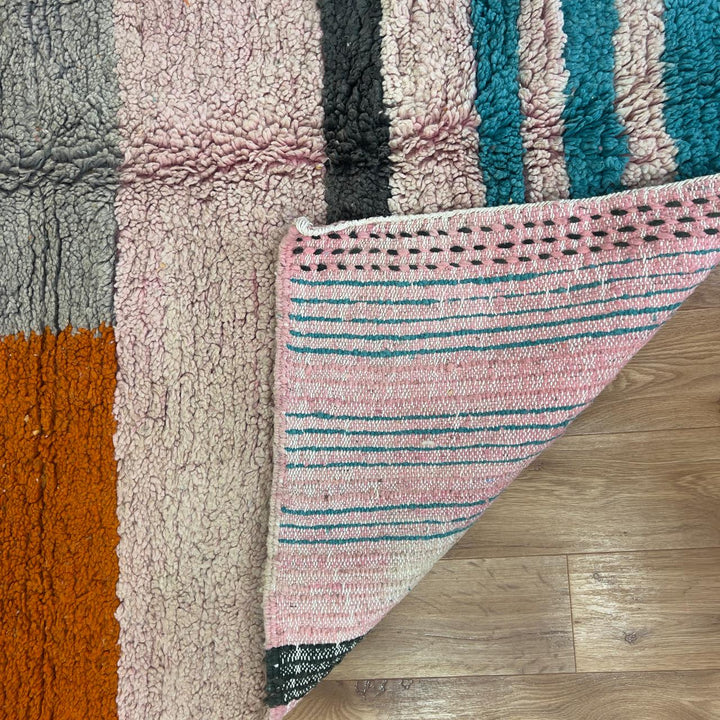 Vintage Moroccan wool rug 7.09 × 4.92 ft with striped design in blush pink, teal, charcoal, and burnt orange tones handmade Berber rug