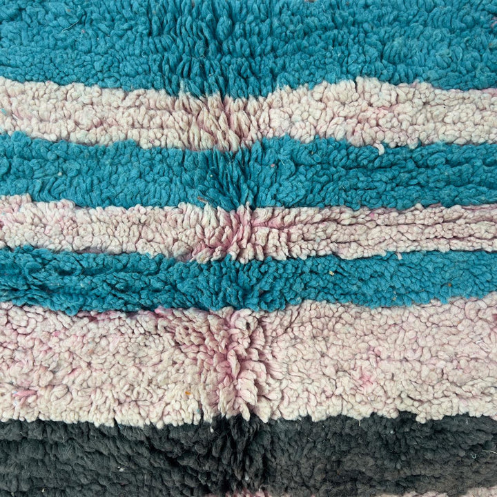 Vintage Moroccan wool rug 7.09 × 4.92 ft with striped design in blush pink, teal, charcoal, and burnt orange tones handmade Berber rug