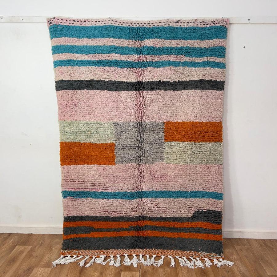 Vintage Moroccan wool rug 7.09 × 4.92 ft with striped design in blush pink, teal, charcoal, and burnt orange tones handmade Berber rug
