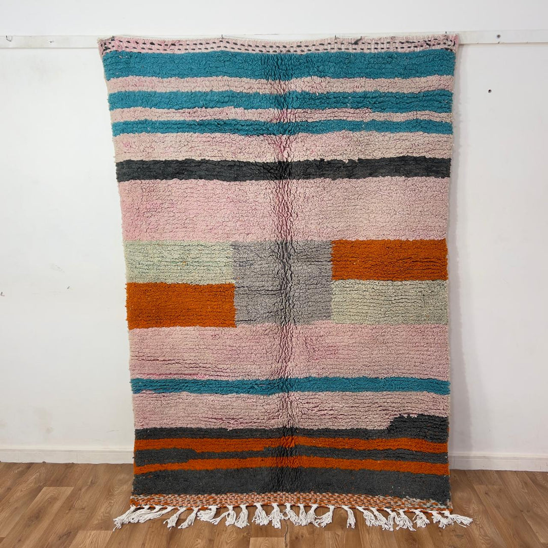 Vintage Moroccan wool rug 7.09 × 4.92 ft with striped design in blush pink, teal, charcoal, and burnt orange tones handmade Berber rug