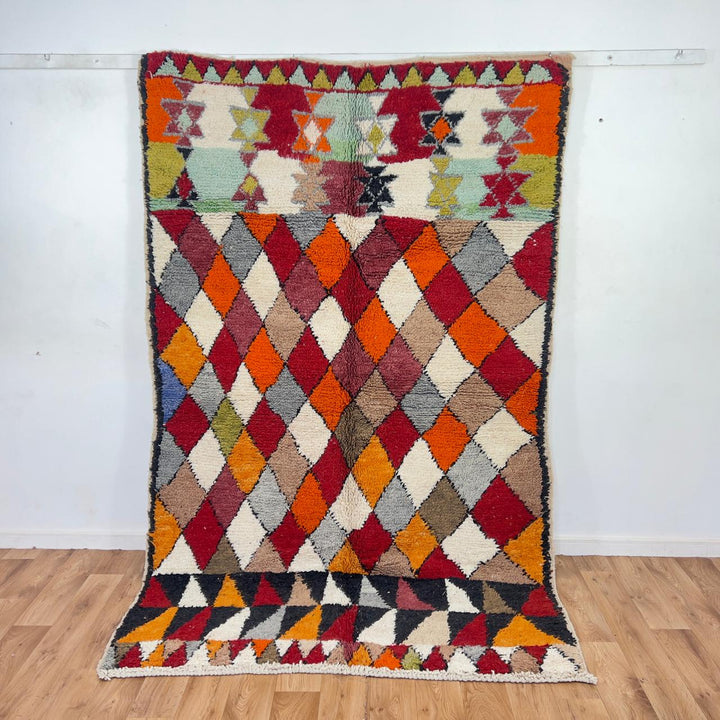 Vintage Moroccan wool rug with colorful geometric diamond and tribal patterns in red, orange and neutral tones, handmade Berber rug