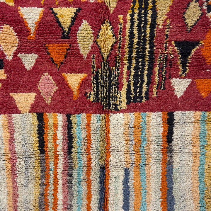 Vintage Moroccan wool rug 8.69 x 5.25 ft Rug 111 with red geometric Berber patterns and multicolor striped lower section, handmade shag rug displayed on wooden floor