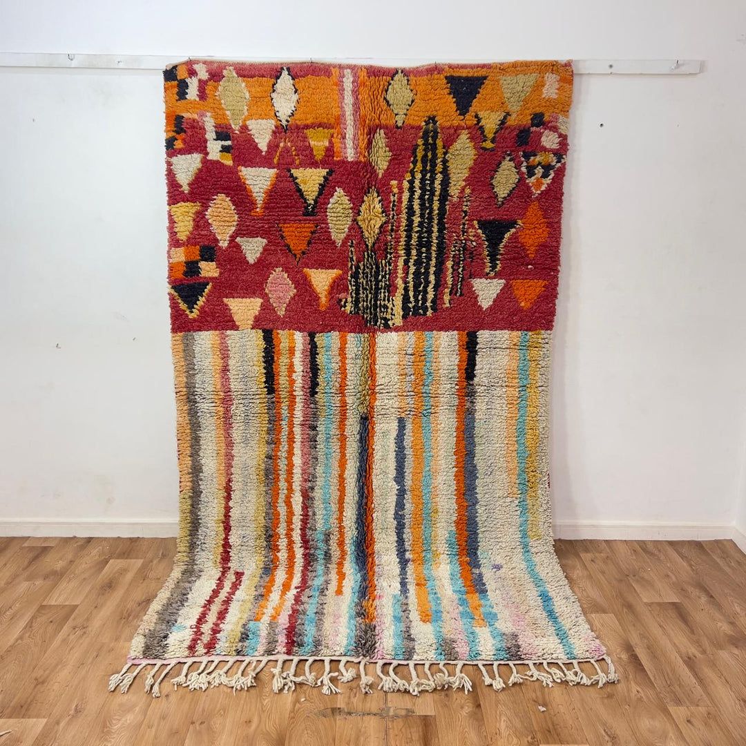 Vintage Moroccan wool rug 8.69 x 5.25 ft Rug 111 with red geometric Berber patterns and multicolor striped lower section, handmade shag rug displayed on wooden floor