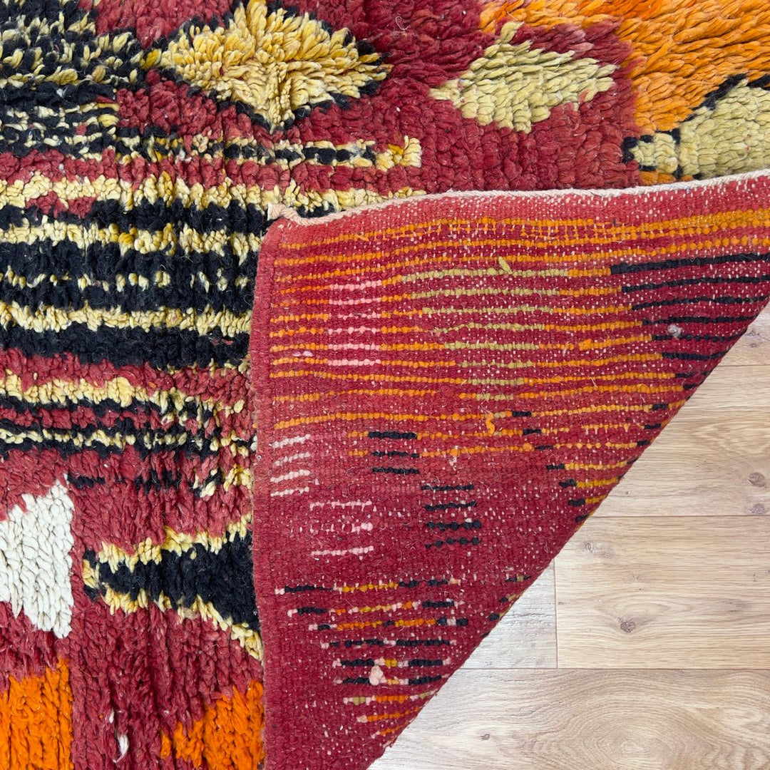 Vintage Moroccan wool rug 8.69 x 5.25 ft Rug 111 with red geometric Berber patterns and multicolor striped lower section, handmade shag rug displayed on wooden floor
