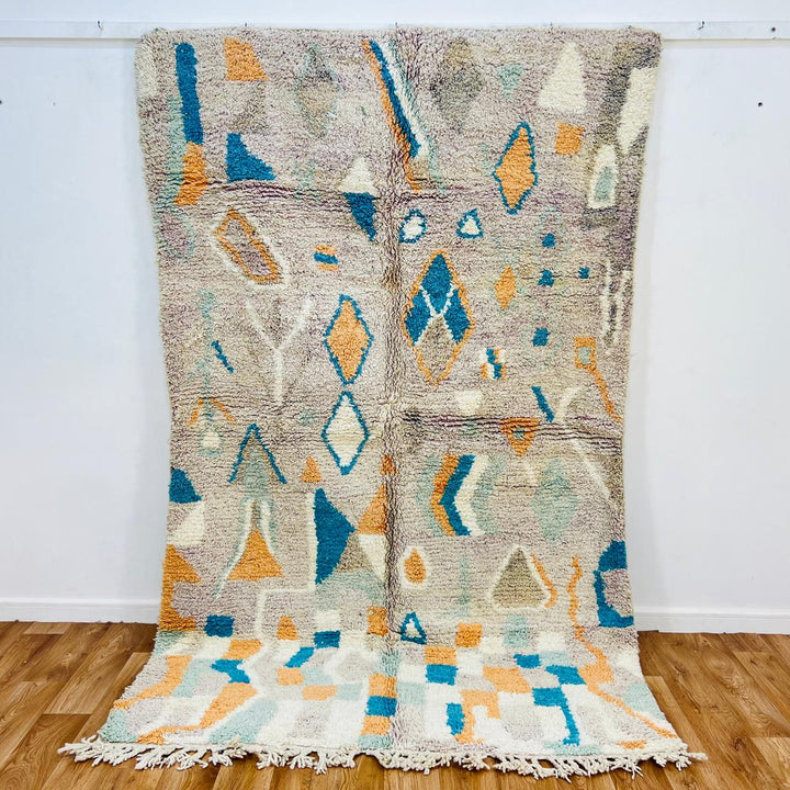 Vintage Moroccan wool rug with abstract Berber geometric pattern in beige, blue, and orange tones — handmade tribal carpet from Morocco.
