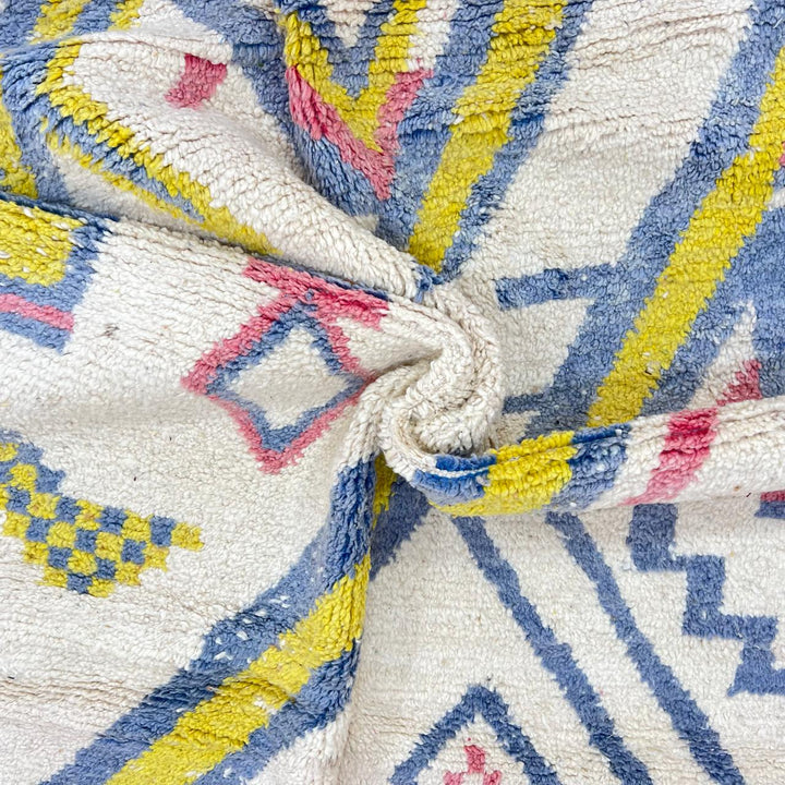 Vintage Moroccan wool rug with ivory base and diagonal geometric patterns in blue, yellow and pink